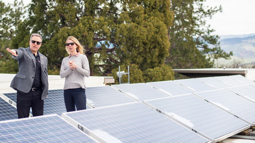 Solar arrays surround President Rick Bailey and Sustainability Director Becs Walker